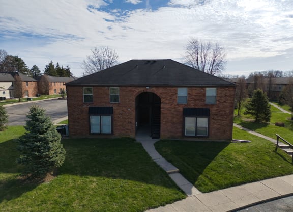 a brick building with a black roof and a sidewalk