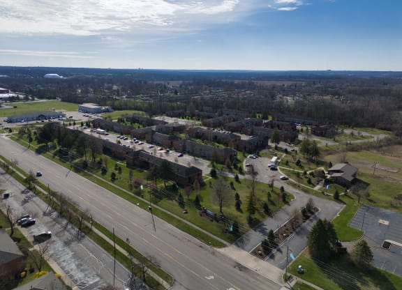 an aerial view of a neighborhood with an empty street and cars on a highway