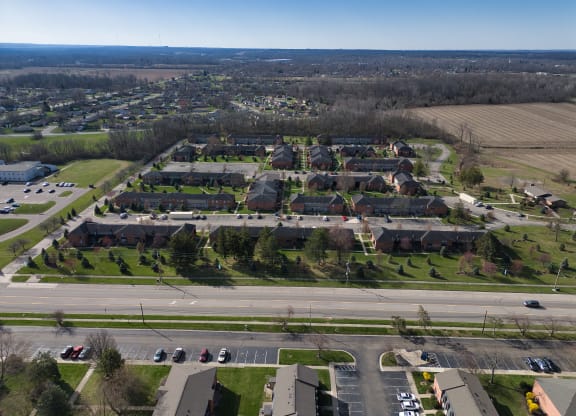 an aerial view of a neighborhood with cars driving on a road and many houses