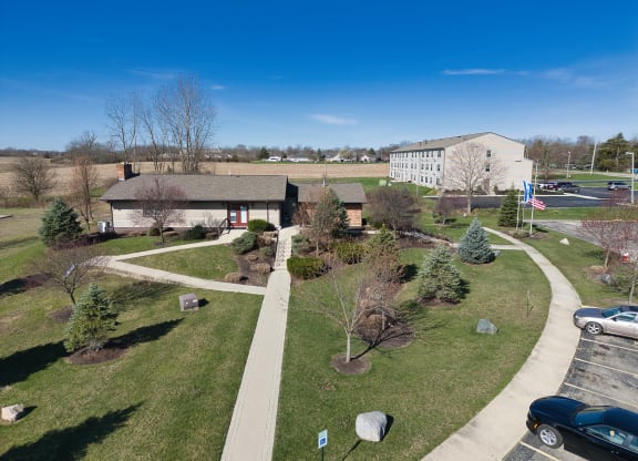 an aerial view of a park with trees and a sidewalk and a building