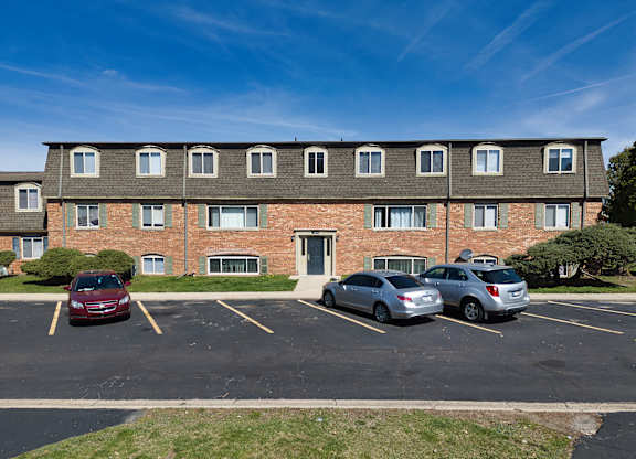 a large brick apartment building with cars parked in a parking lot