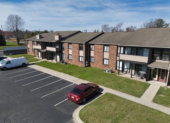an apartment building with a red car parked in a parking lot
