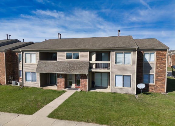 an exterior view of an apartment building with a sidewalk and grass