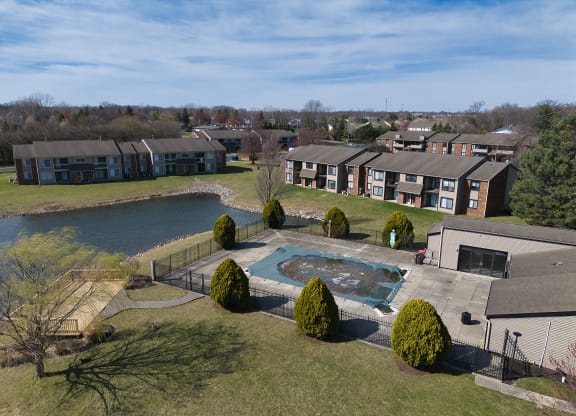 an aerial view of an apartment complex with a swimming pool and a lake