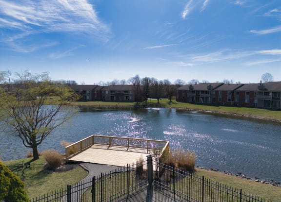 the view of a pond with a bridge in front of an apartment building