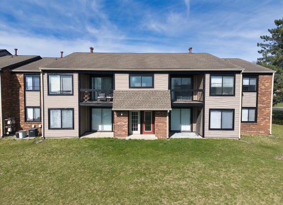 a large apartment building with a lawn and a blue sky