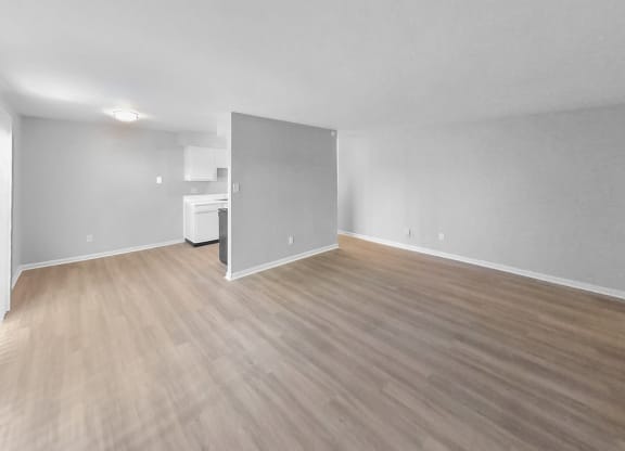 the living room and kitchen of an empty apartment with wood flooring