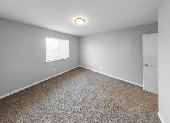 an empty room with carpet and a window