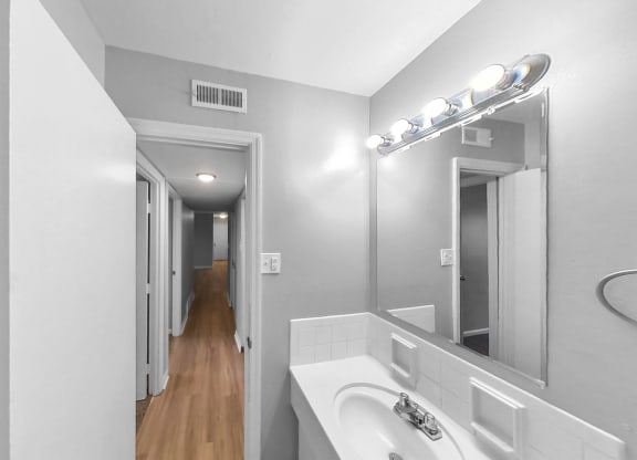 a bathroom with a sink and a mirror and a hallway