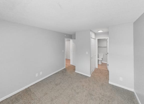 the living room of an apartment with white walls and carpet