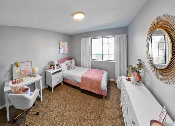 a bedroom with a bed and a desk and a window