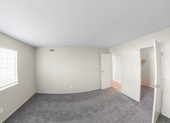 an empty bedroom with a large window and a closet