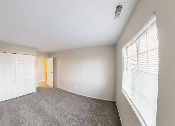 an empty living room with a large window and a white door