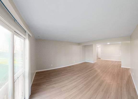 an empty living room with wood flooring and a large window
