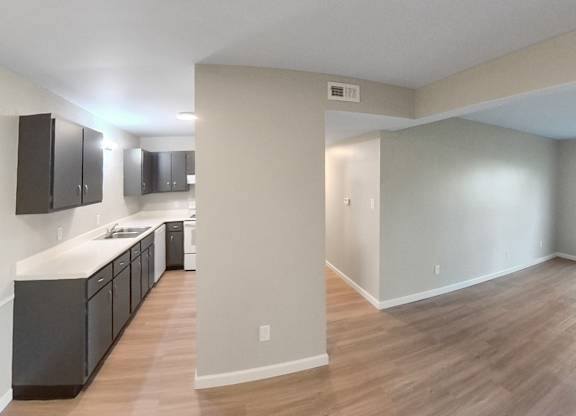 an empty living room and kitchen with wood flooring and a window