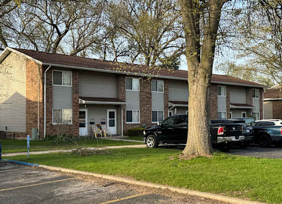 A black car is parked in front of a brick apartment building.