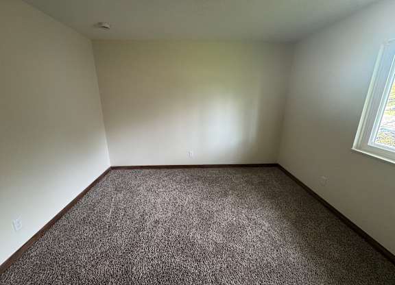 A room with a carpeted floor and a window.
