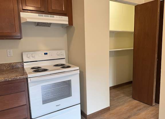 A white stove is in a kitchen with a white oven and a brown cabinet.