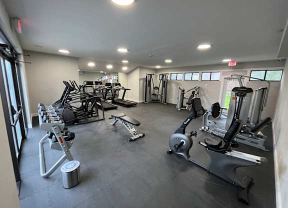 A gym with a variety of equipment including treadmills, weights, and exercise machines.