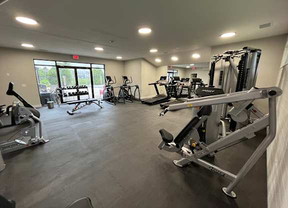 A gym with a variety of exercise equipment including treadmills, stationary bikes, and weight machines.