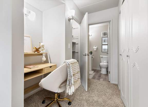 a bedroom with a desk and a chair and a bathroom with a toilet