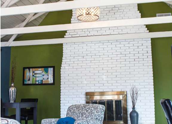 a living room with a white brick fireplace and green walls
