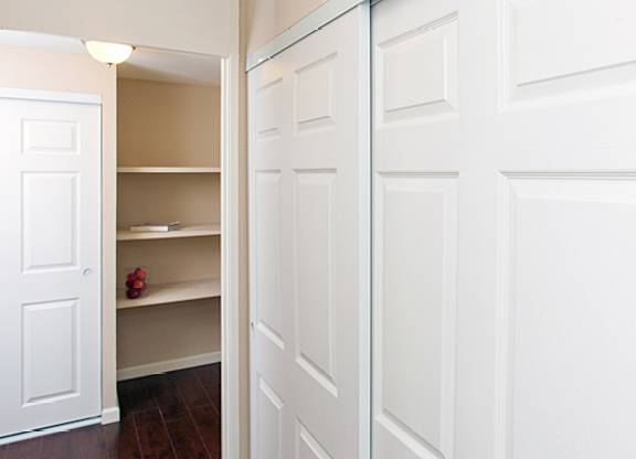 A white door is open to a hallway with a shelf and a pair of red shoes on it.