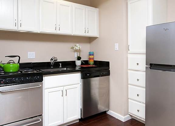 A kitchen with white cabinets and a black countertop.