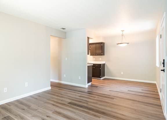 A room with wooden flooring and a kitchenette in the corner.