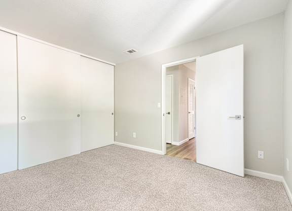 A white room with a carpeted floor and a white door.