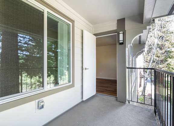 A balcony with a sliding glass door and a black railing.