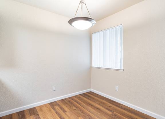 A room with a window and a wooden floor.
