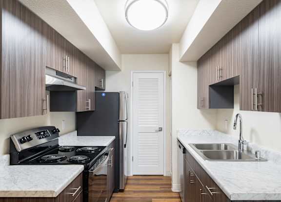A kitchen with a white counter top and dark wood cabinets.