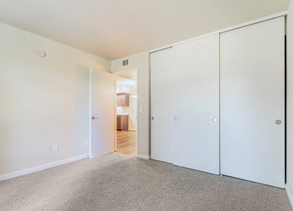 A white room with a carpeted floor and a white door.