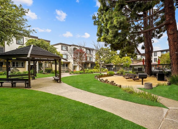 a park with a gazebo and benches in front of some apartments