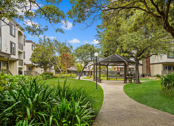 a park with a gazebo and trees in front of apartment buildings