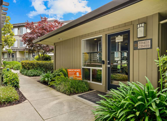 the entrance to an office building with a sidewalk and plants