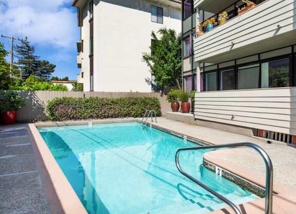 A small pool with a metal ladder sits in front of a building.