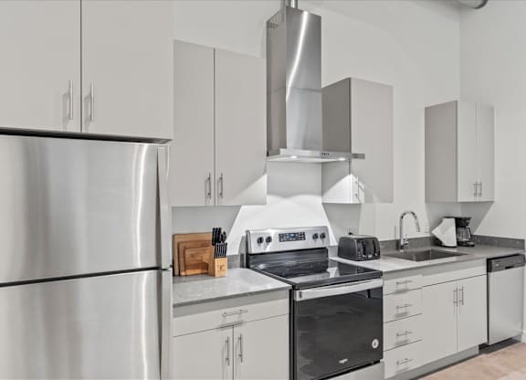 A modern kitchen with stainless steel appliances and white cabinets. at Paperbox Lofts, Salt Lake City, UT, 84101