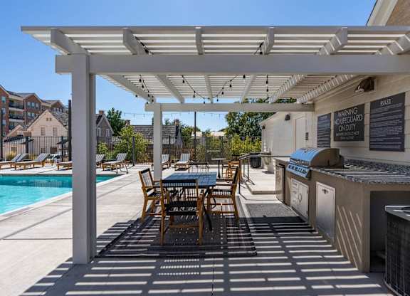 a patio with a grill and a table with chairs and a pool at City View St. George Apartments, St George, UT, 84770