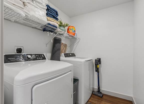 a washer and dryer in a small laundry room with white walls and wood at City View St. George Apartments, St George, Utah