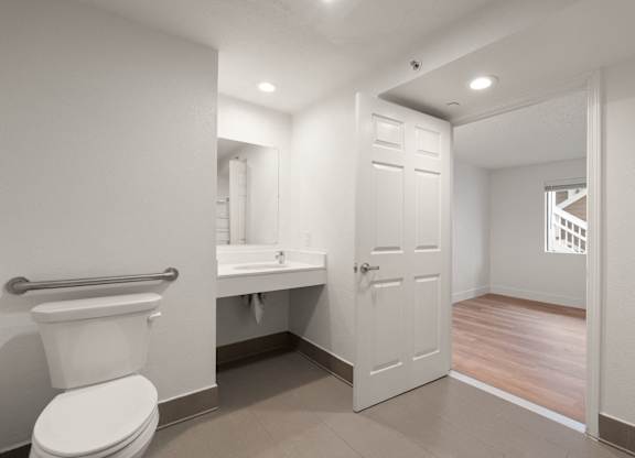 A white toilet is in a small bathroom with a white door at AVIA Lofts on Parkway Apartments, Washington, 98662