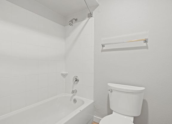 a white bathroom with a tub and a toilet at AVIA Lofts on Liberty Ridge Apartments, Jacksonville, FL, 32256