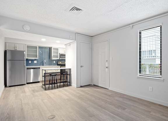 the living room and kitchen of an apartment with a crib and a refrigerator at AVIA Lofts on Liberty Ridge Apartments, Jacksonville, FL, 32256