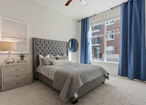 a bedroom with a bed and a window with blue curtains at 200 City View, Provo, UT