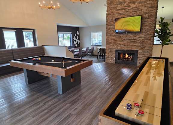 Community room with a pool table and a TV mounted above a fireplace at Avia Lofts at Maple Road, Amherst, 14221