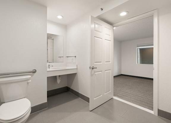 A white toilet is in a small bathroom with a white sink and a white door at AVIA Lofts on Parkway Apartments, Vancouver, WA, 98662