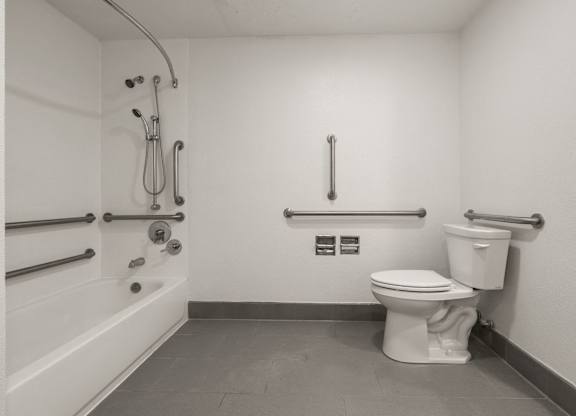 A white toilet in a bathroom with a shower head and hand held shower at AVIA Lofts on Parkway Apartments, Vancouver, WA, 98662