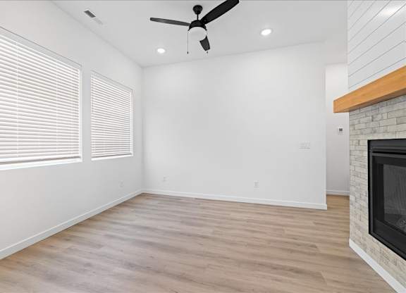 A room with a fireplace and a ceiling fan.at Alante Homes at Spring Run, Caldwell, 83607