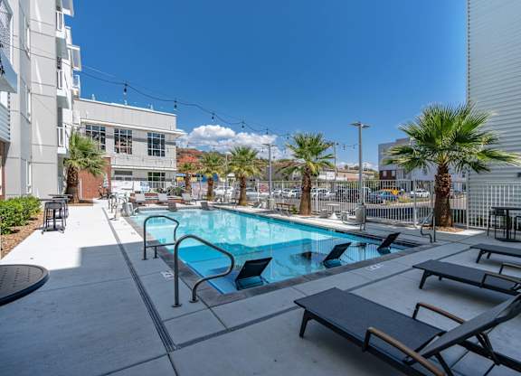 a swimming pool with lounge chairs and palm trees in front of a building at 605 Place Student Housing & Co-Living, St George, Utah